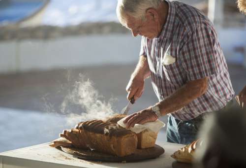 Person Slicing Into Fresh Bread Photo