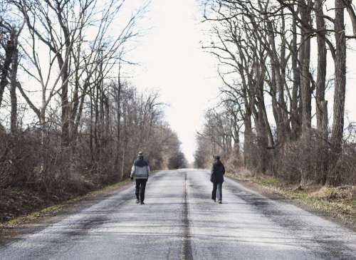 Two People Walking On Empty Road Photo