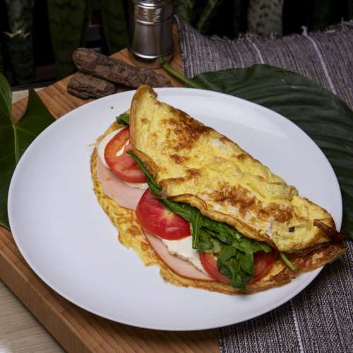 Homemade omelet with ham, cheese, spinach and tomatoes