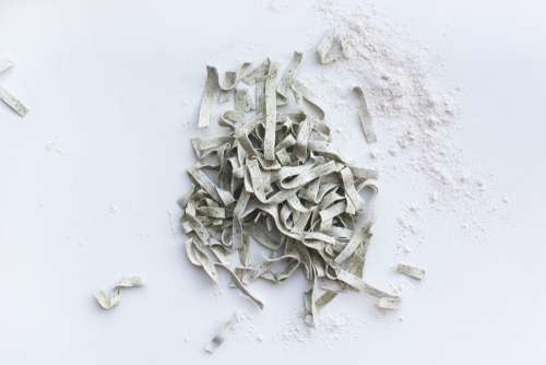 Pasta tagliatelle covered by flour on a white background