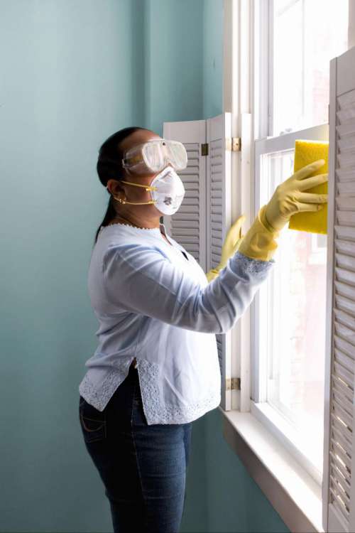 Woman in mask and gloves disinfecting surfaces