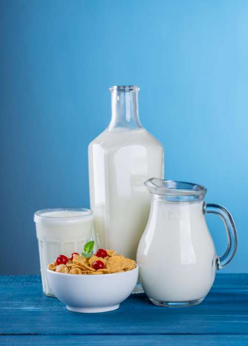 Close up of a glass, a pitcher and a bottle containing milk