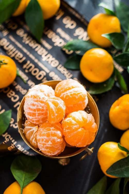 overhead view of peeled mandarins in a brass fruit bowl