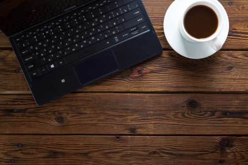 Overhead view of a laptop alongside a cup of coffee