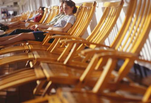 Young couple sitting on deck chairs on cruise ship.