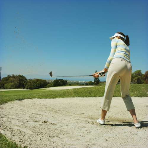 Golfer taking a shot from a sand bunker