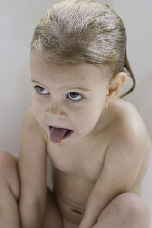 Girl (3-4), sticking tongue out in bathtub