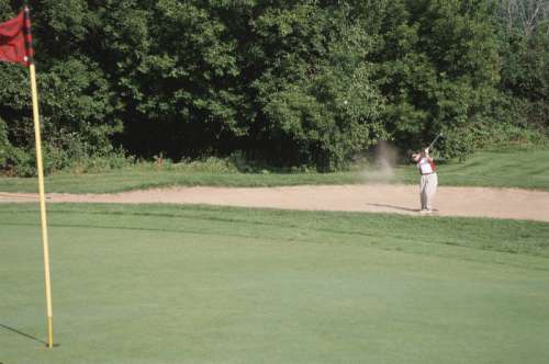 Golfer hitting ball out of sand trap