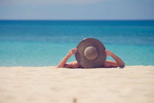 Woman Wearing Sun Hat On A White Sandy Beach