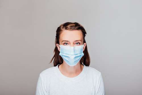 Woman In Grey Sweater Wearing Disposable Face Mask Photo