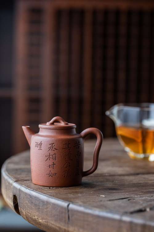 A Ceramic Teapot On A Wooden Table With Chinese Characters Photo