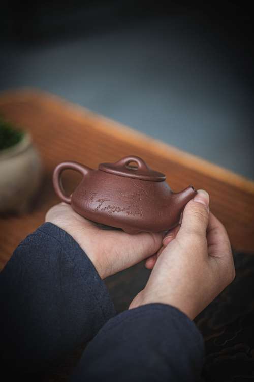 Hands Holding A Carved Chinese Teapot Photo