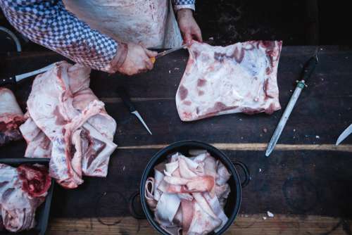 Butcher cutting pork meat top view