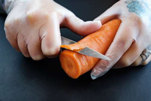 Tattooed Hands Cut A Carrot Photo