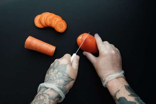 Tattooed Hands Chop Food With Gloves Photo