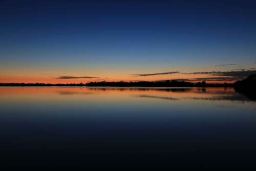 Blue And Orange Sky Over Still Water Photo