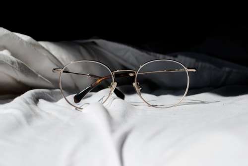 Pair Of Glasses On A Bed Photo