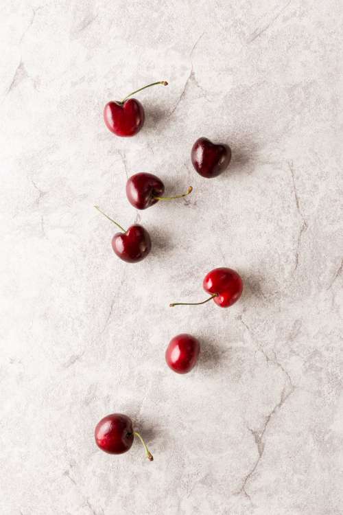 Cherries Scattered Across Marble Surface Photo