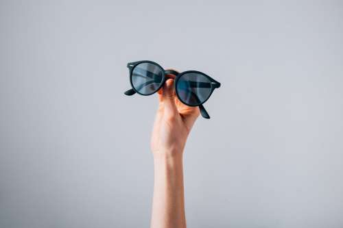 Pair Of Sunglasses Held In Front Of Grey Background Photo