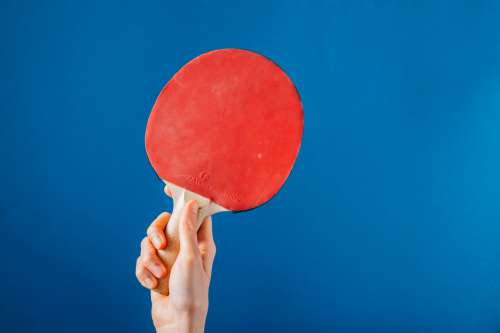 Hand Holding Ping Pong Paddle On Blue Background Photo