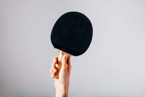 Hand Holding Ping Pong Paddle On Grey Background Photo