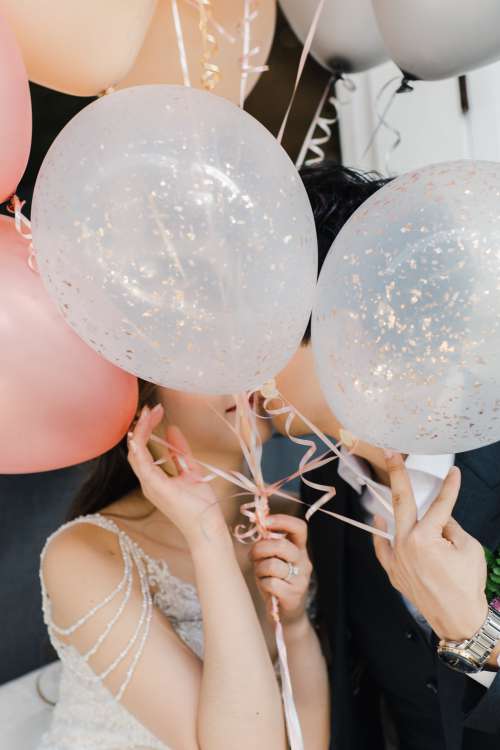 Shy Couple Kisses Behind Balloons Photo