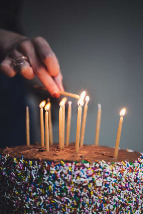 Womans Hand Liting Birthday Candles Photo