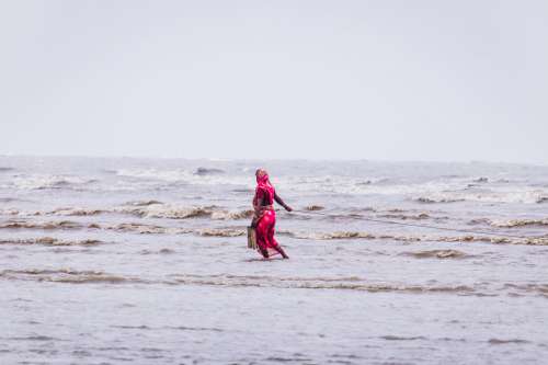 Woman In Red Walking Through Shallow Water Photo