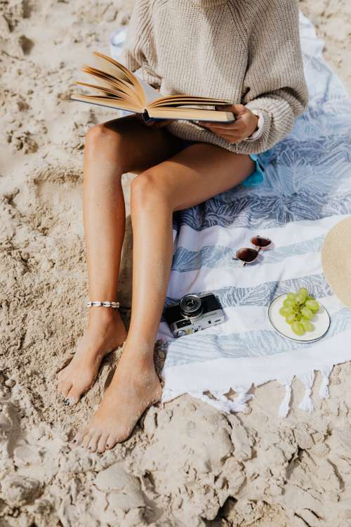 A woman reads on the beach in the summer