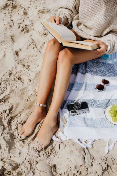 A woman reads on the beach in the summer