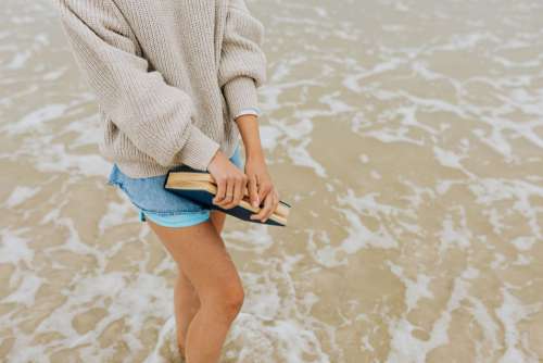 A young woman with a book on the seashore