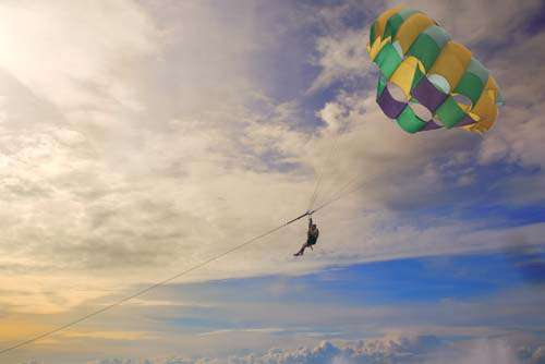 Couple Parasailing With Colorful Parachute And Dramatic Sky