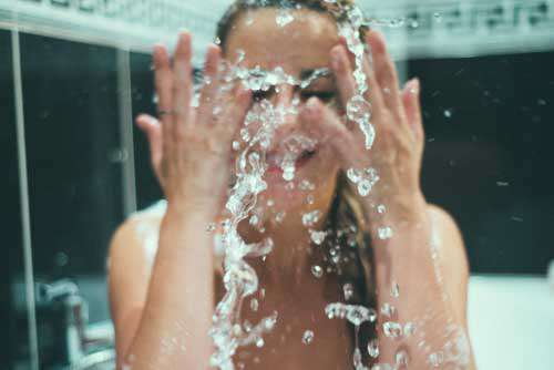 Girl Splashing Face With Water In A Bathtub