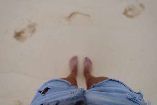 Girls Feet In Sand Wearing Denim Shorts