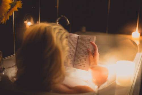 Girl Reading Book In A Bothtub With Candles And Wine