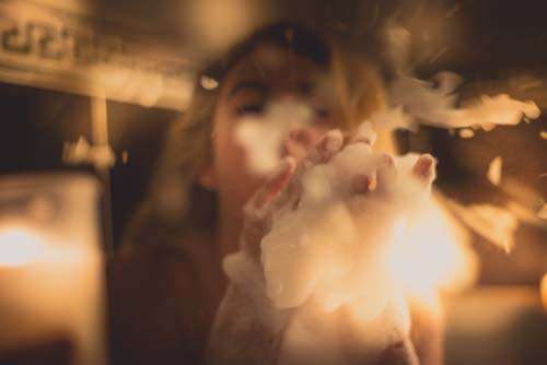 Girl Playfully Blowing Soap Suds With Candles