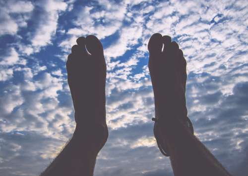 Mans Feet In The Air With Blue Cloudy Sky