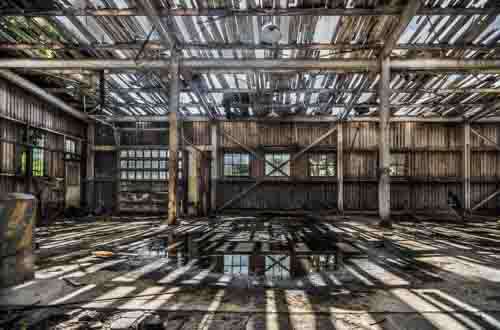 Derelict Warehouse With Sun Shining Through Broken Roof