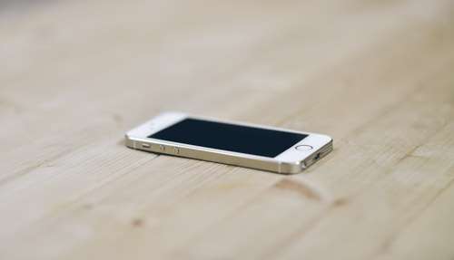 White iPhone 5s On clean Wooden Desk