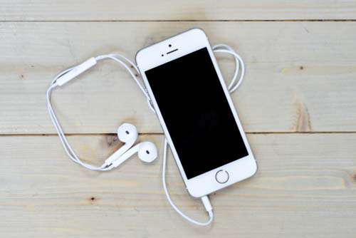 White iPhone On Wooden Desk With Headphones