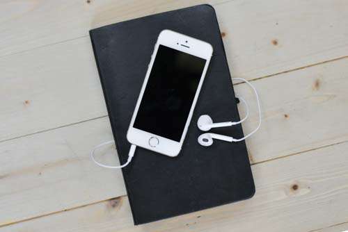 White iPhone On Black Book With Headphones