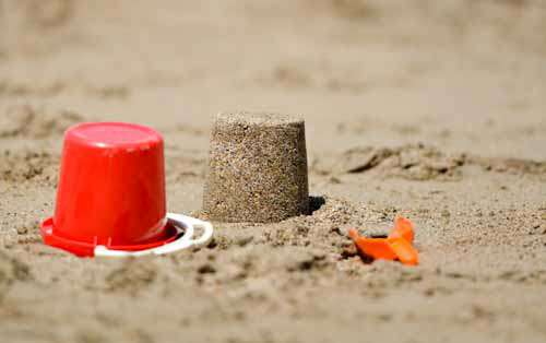 Sand Castle And Red Bucket On Beach