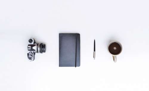 Camera, Notebook, Pen And Coffee On Desk