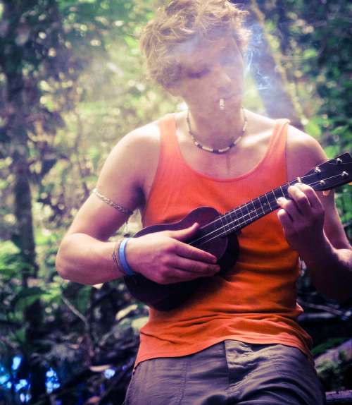 Man Playing Ukalele Whilst Smoking In A Forest