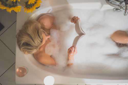 Girl Reading Whist Relaxing In A Bubble Bath tub