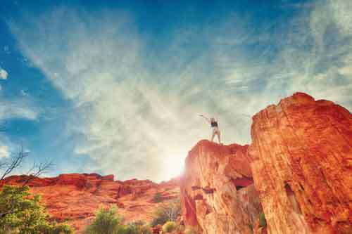 Woman Standing On Red Rocks Celebrating Success