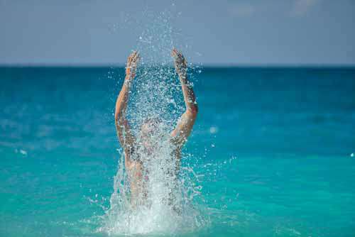 Happy Man Splashing Water In The Ocean