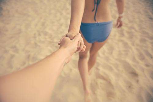 Lovers Holding Hands On Beach With Bikini