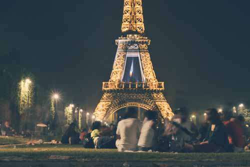 Group Of People Socialising In Front Of Eifel Tower At Night