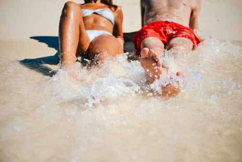 Couples Feet Getting Playfully Splashed By The Sea